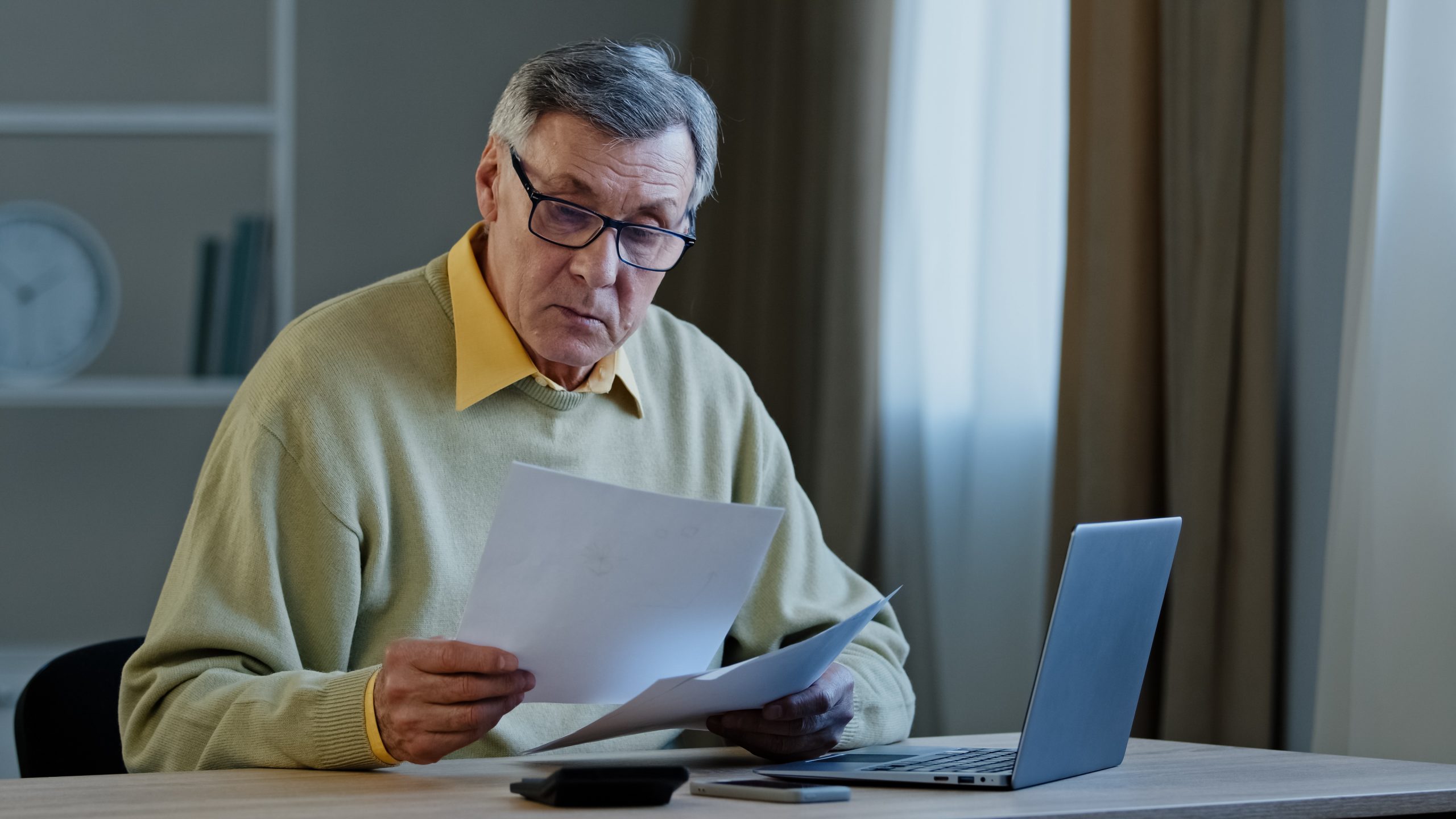 Older male reviewing documents at his computer