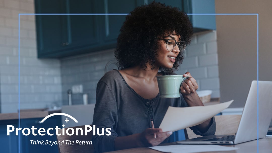 A woman with a cup of coffee and a piece of paper looking at her computer with a ProtectionPlus logo in the corner